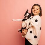 cheerful young caucasian woman holding black white bulldog while standing pink background with space text love dog owner concept 1