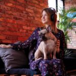 happy blonde woman dress sitting with her cute pug handmade sofa listening music room with loft interior