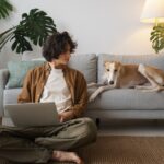 man working home from laptop with greyhound dog couch